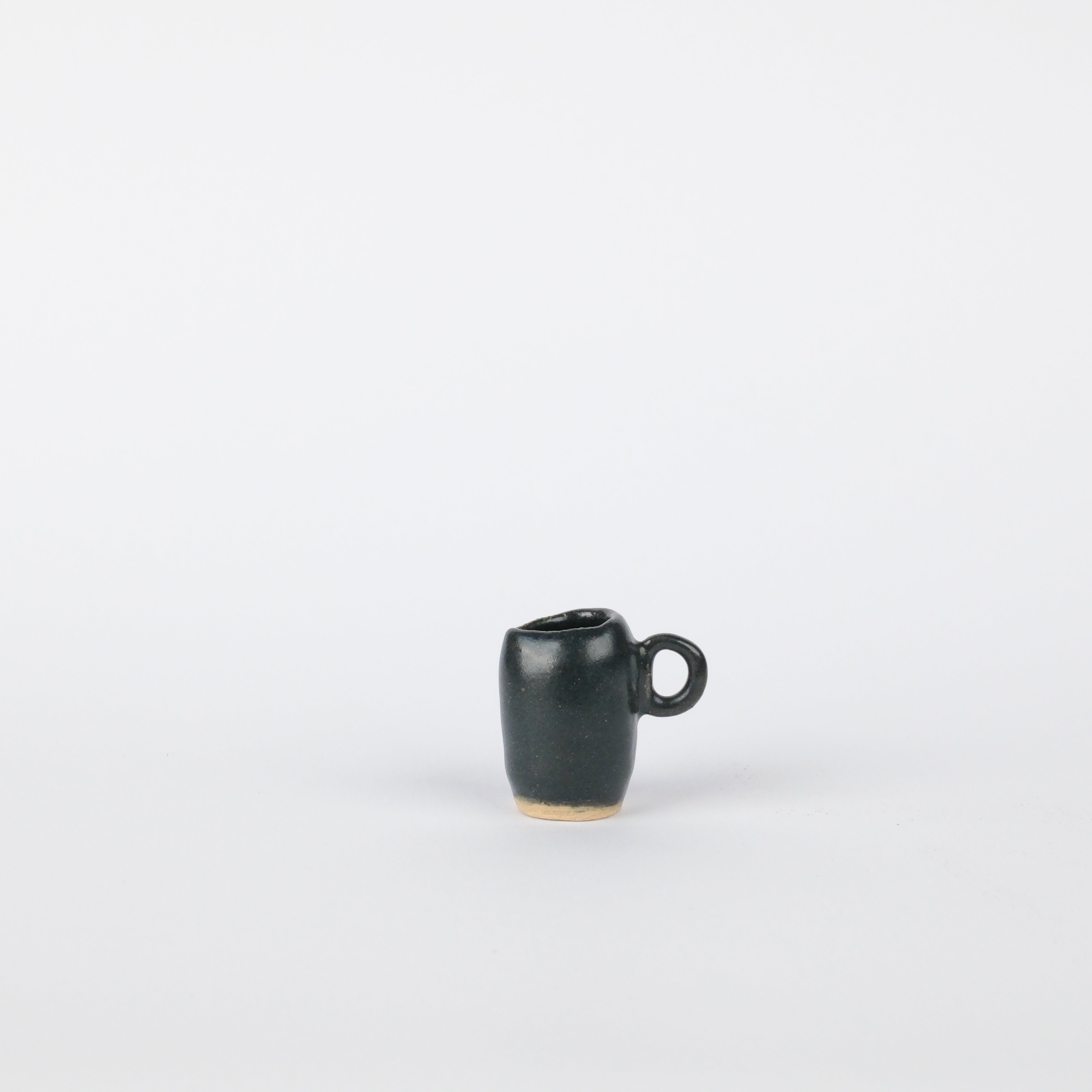 Handcrafted 25mm black stoneware tiny vase with a small side handle, set against a plain white background.
