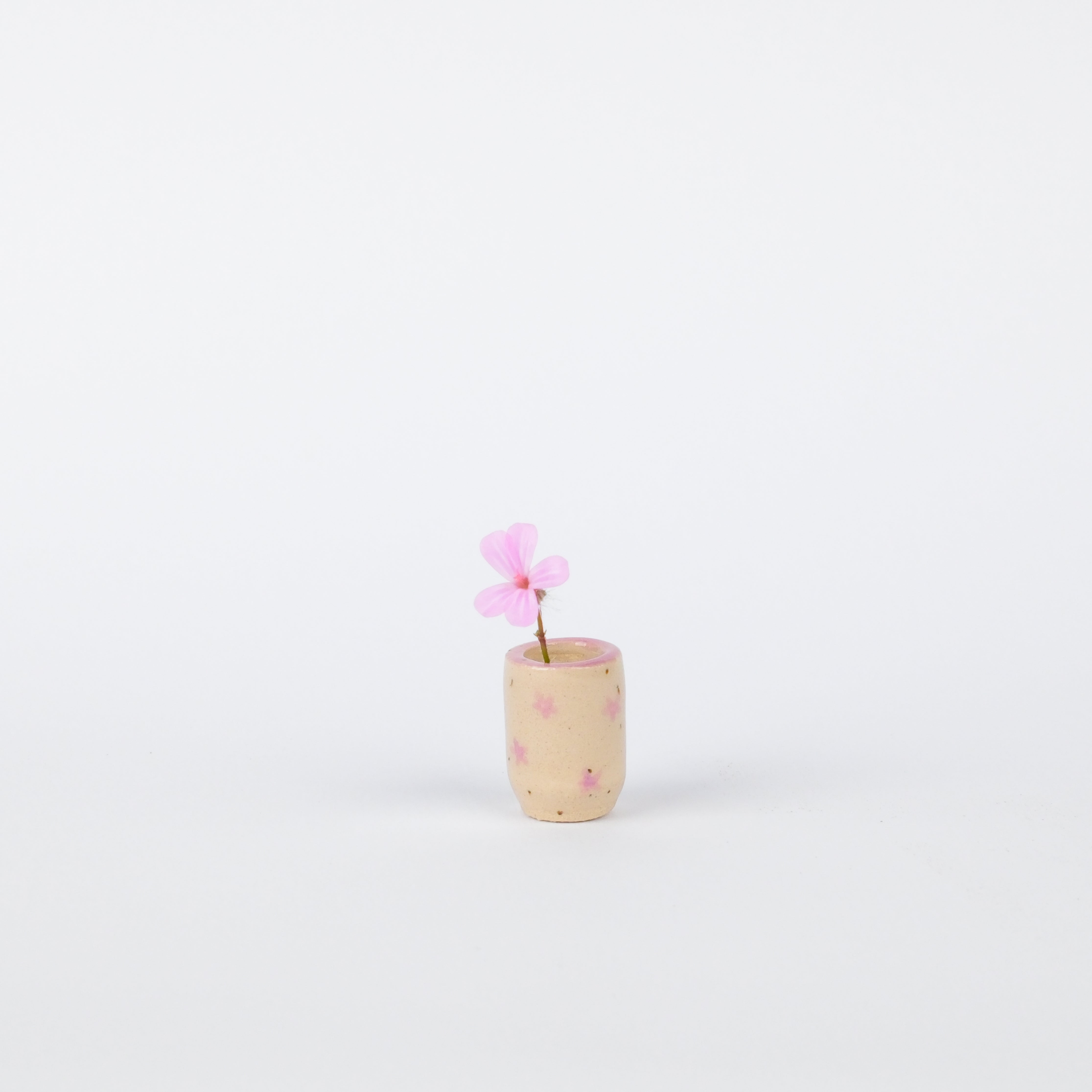 Hand-painted 20mm speckled stoneware vase with pink floral accents and a single pink flower on a white background.