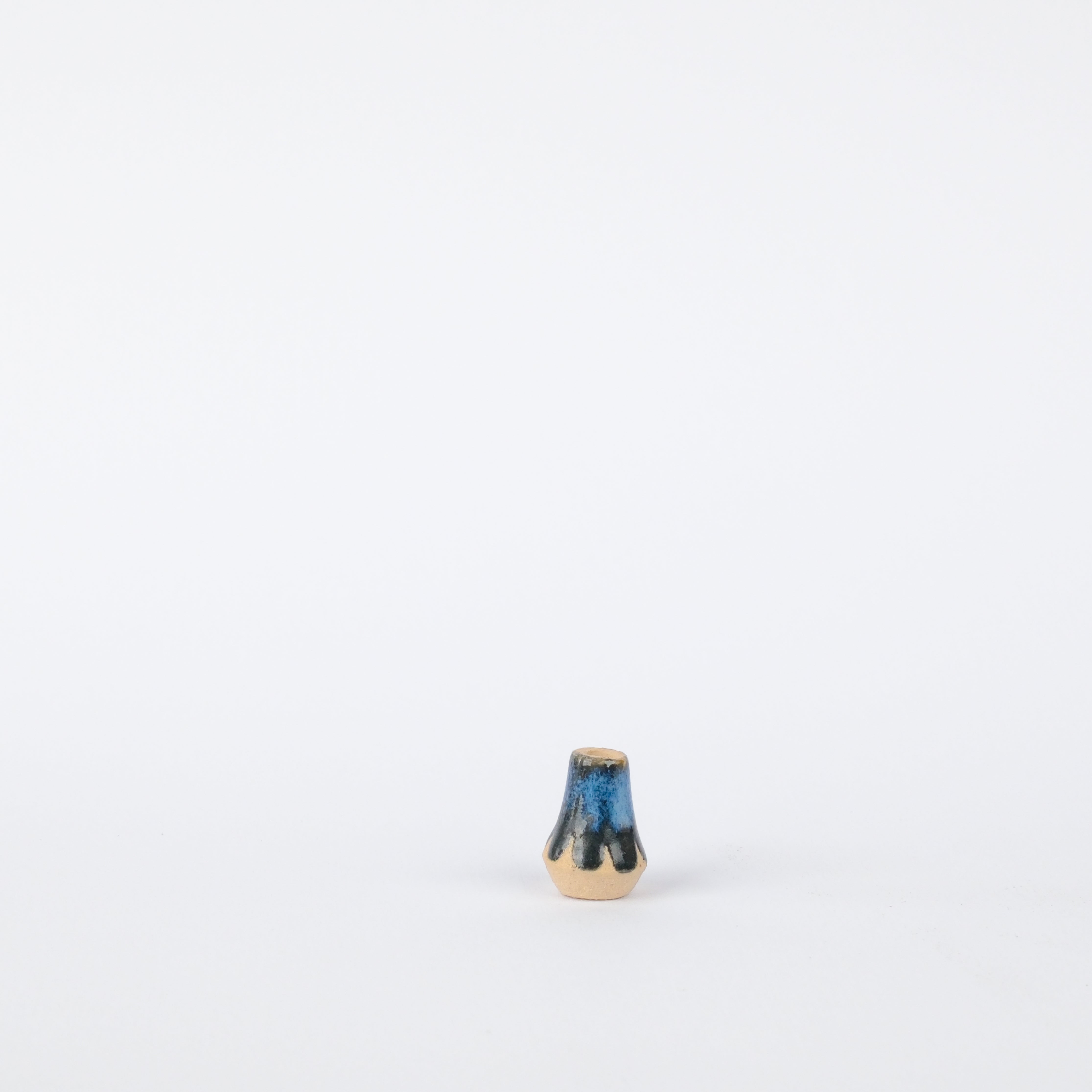 Handcrafted 17mm stoneware vase with a blue and black drip glaze finish on a natural beige base.