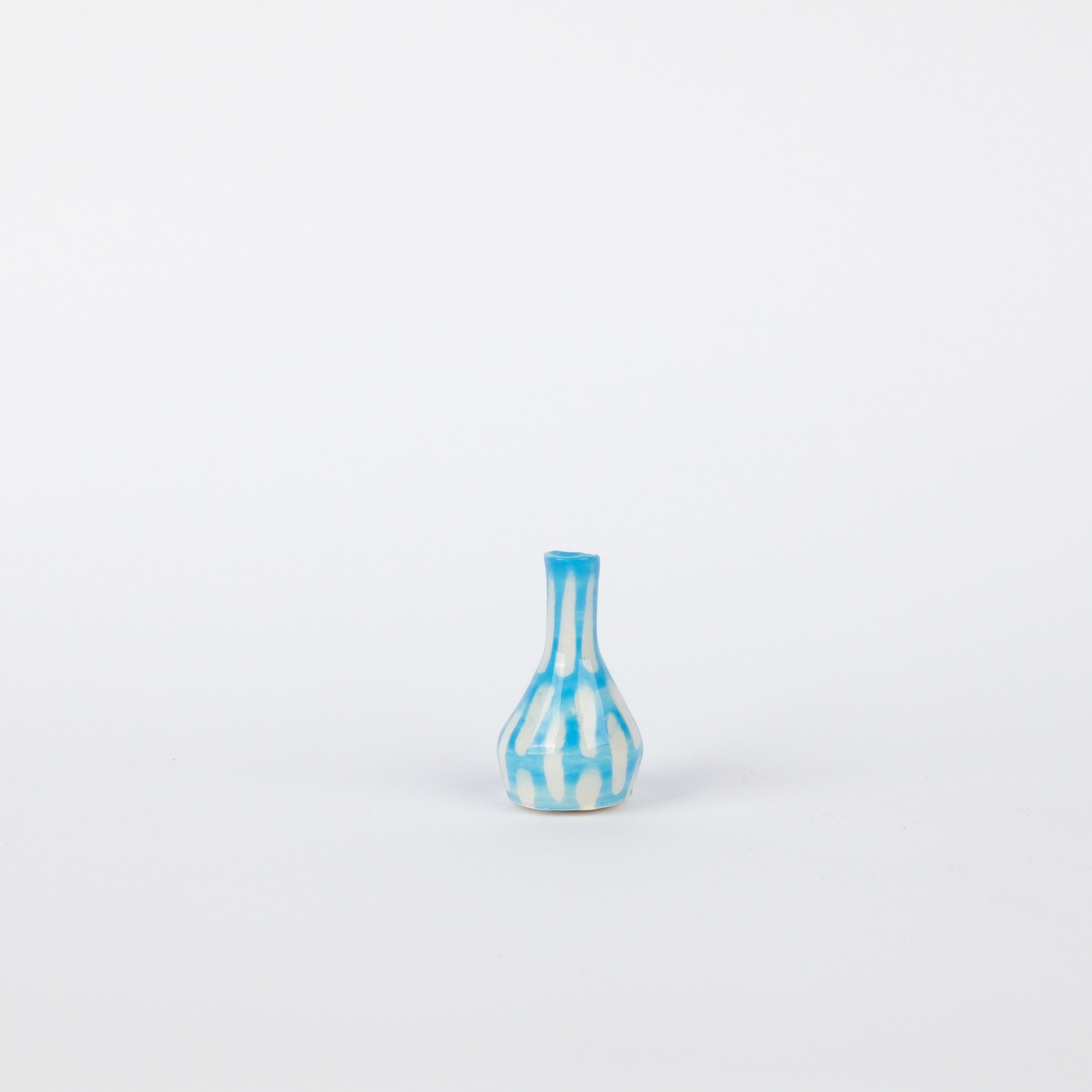 Handcrafted 32mm stoneware bud vase featuring a white base with vertical blue painted stripes on a white background.