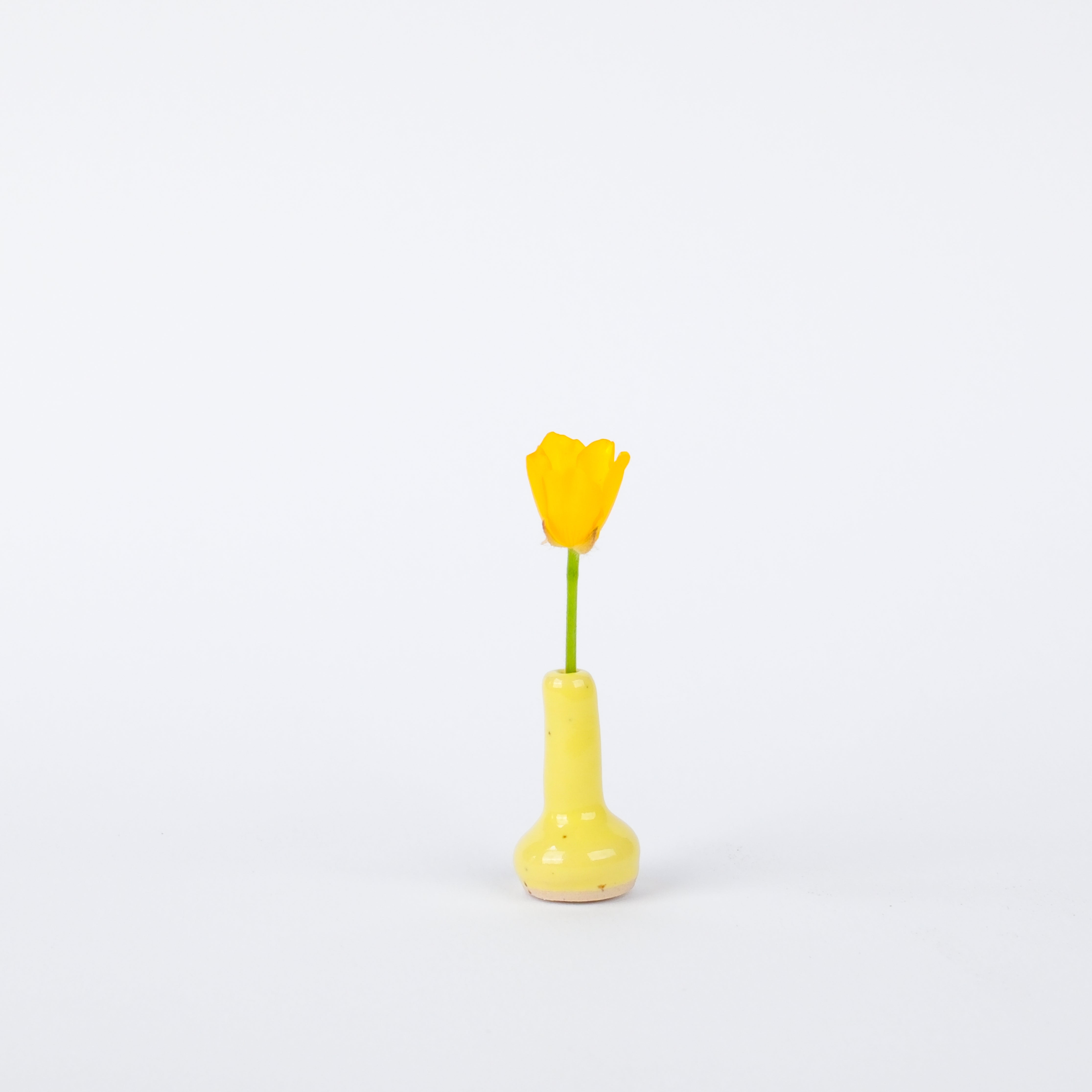 Handcrafted 28mm yellow stoneware vase with a glossy finish, holding a single bright yellow flower.